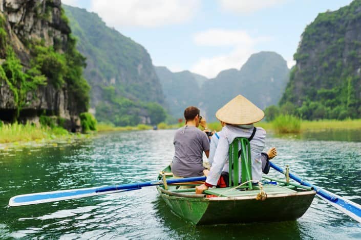 Tourists+traveling+in+small+boat+along+the+ngo+dong+river+at+the+tam+coc+portion,+ninh+binh+province,+vietnam.